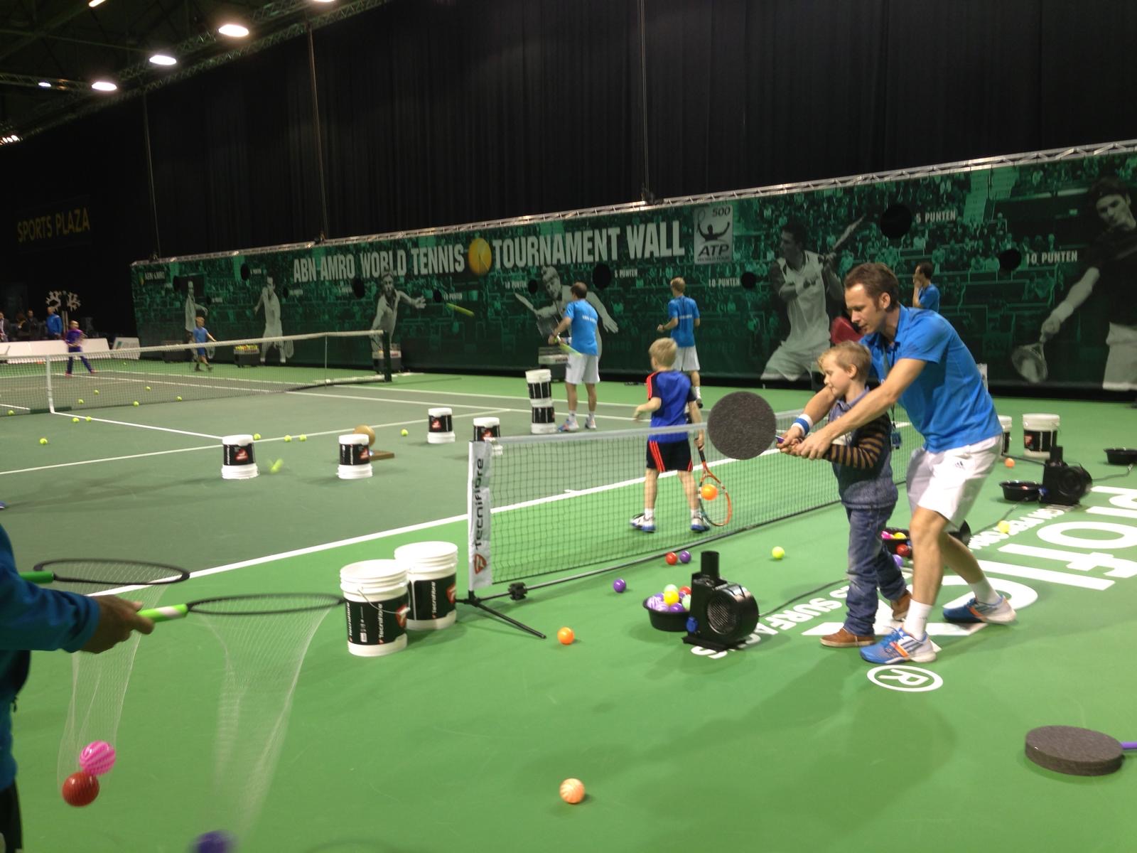 Roland Laurense helpt een jong kind bij het slaan van een zwevende bal tijdens floater tennis op het ABN AMRO World Tennis Tournament