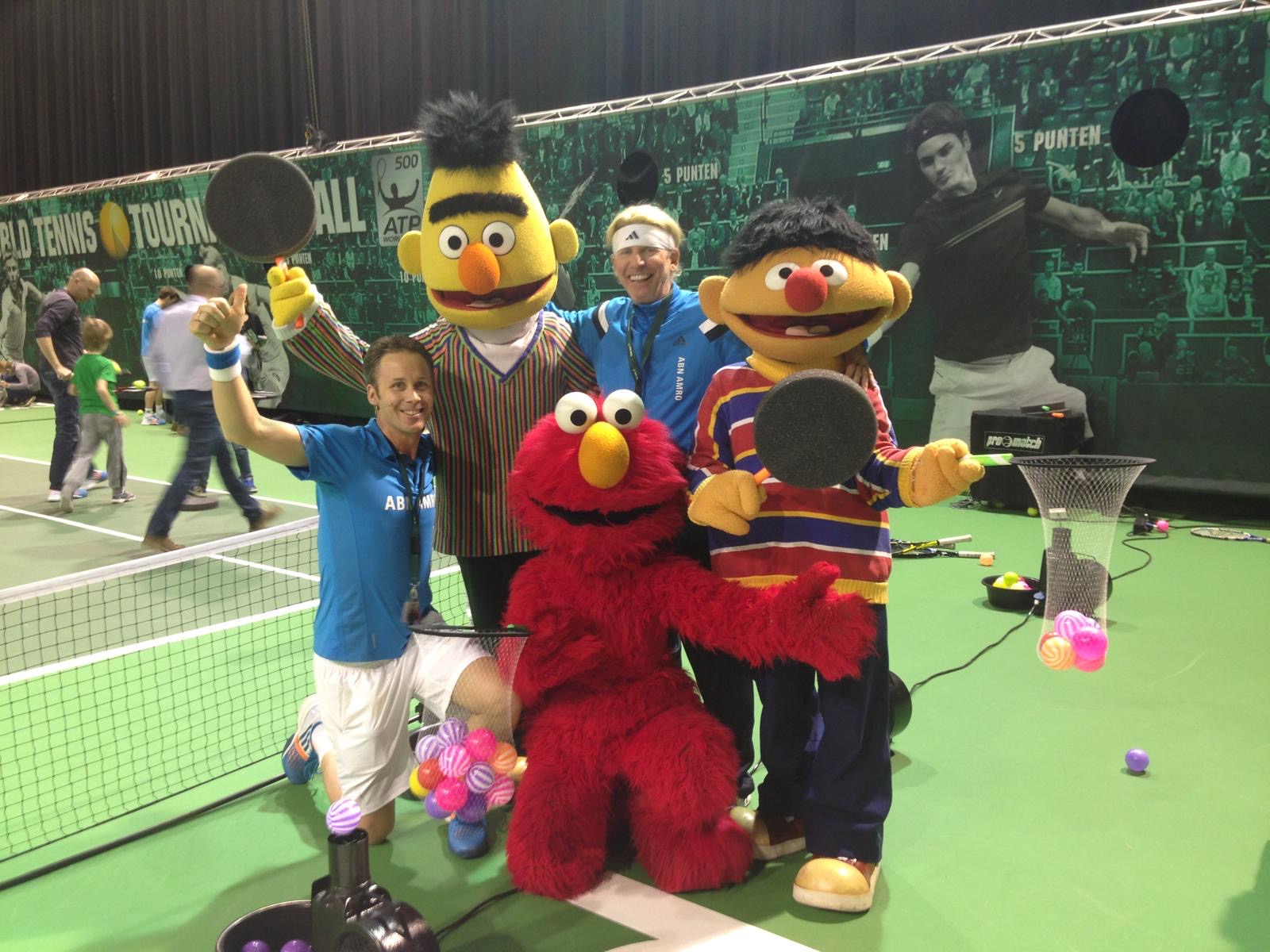 Roland Laurense met tennispro en Sesamstraat-mascottes Bert, Ernie en Elmo op de baan bij het ABN AMRO toernooi